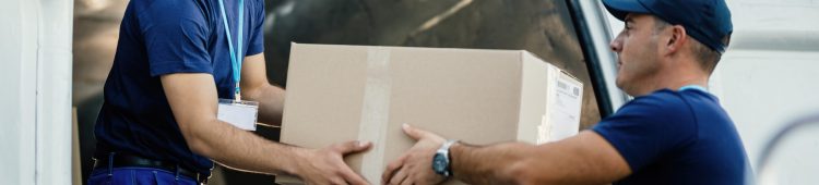 Delivery men loading carboard boxes in a van while getting ready for the shipment.